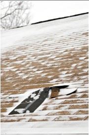 Damaged roof with thin layer of snow